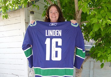 ICAN president Lana Banham stands with the autographed Trevor Linden retired Vancouver Canucks jersey available at the Giving Back Golf Tournament.