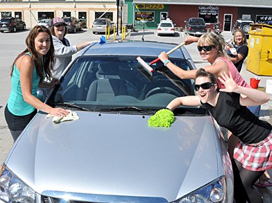 Members of the Killer Rollbots wash a car at their car wash fundraiser.