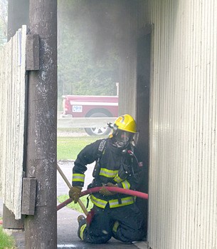 A firefighter prepares to douse the flames inside the public washroom at Kinsmen Beach.