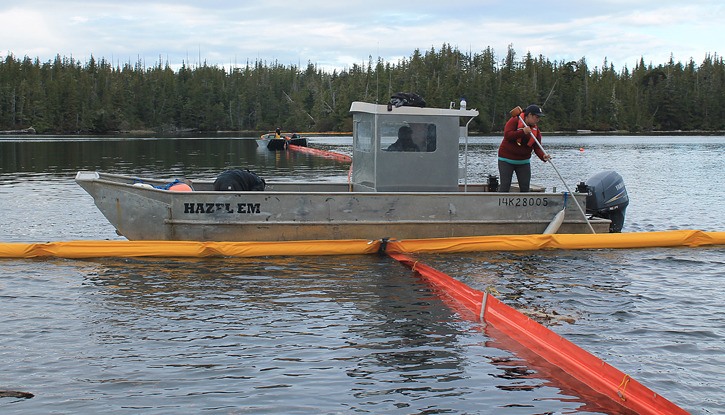 Tracy Robinson tends oil containment booms at Gale Creek near Bella Bella