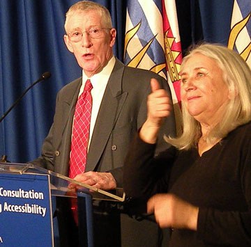 Retired London Drugs CEO Wynne Powell speaks at the B.C. legislature with a sign-language interpreter: 'This is not out of the ordinary. This is how we should operate as a society.'