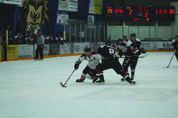 A Castlegar Rebel squeezes by Rockies' defenceman Peter Matthews