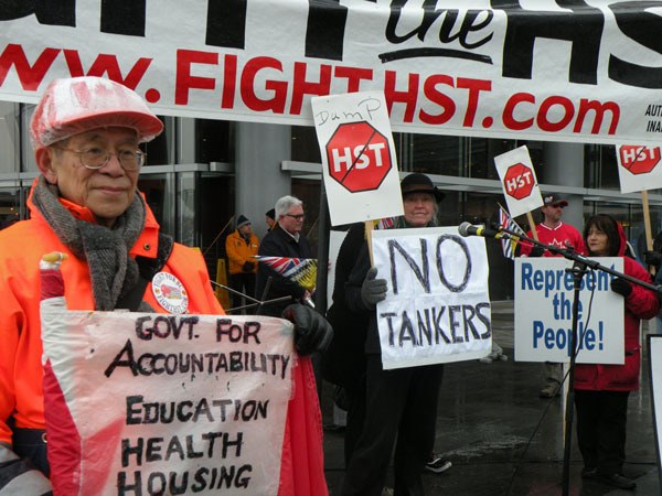 Fight HST organizer Chris Delaney (background) prepares to speak to an eclectic group of protesters outside the Vancouver convention centre.