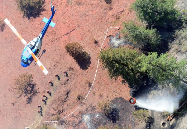 Helicopter drops water on a hot spot as BC Forest crews wait on the ground to move in at the White Lake fire near Penticton in late July.