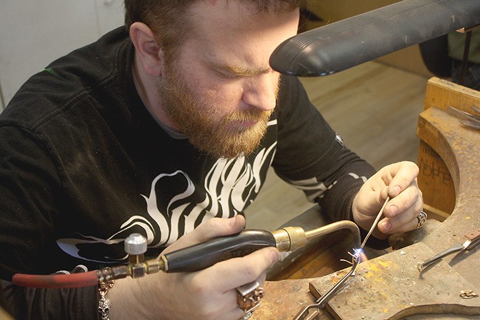 Brandon Szott of Fairmont Goldsmith carefully works on a piece at their shop.