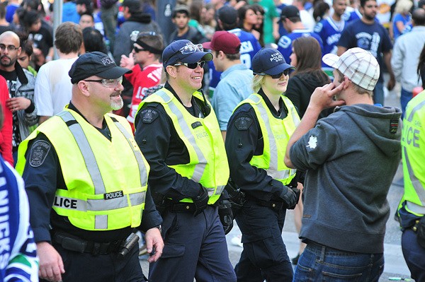 Members of the RCMP and the Abbotsford police (left) patrol Granville Street early Wednesday evening before the post-Stanley Cup riots in downtown Vancouver.