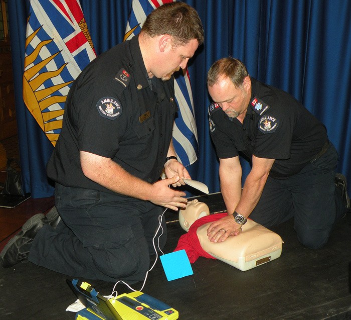 Paramedics demonstrate automated defibrillator. When case is opened