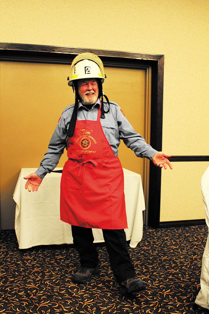 Tim Strub poses in the signed apron and helmet he received as going away gifts from the Radium volunteer fire department.