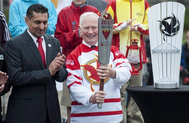 Governor General of Canada David Johnston (right) holds the Canada Winter Games torch as Minster of State (Sport) Bal Gosal looks on