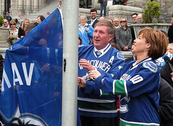 Speaker Bill Barisoff and Premier Christy Clark raise the Vancouver Canucks flag outside the B.C. legislature Tuesday.