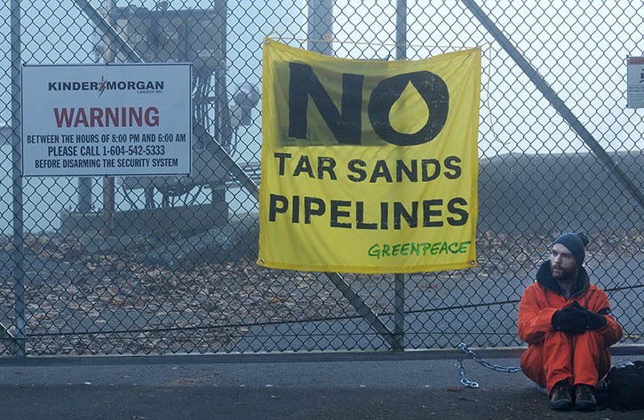 Greenpeace protester Benjamin Zielinski sits chained to fence at Trans Mountain pipeline's Burnaby oil terminal