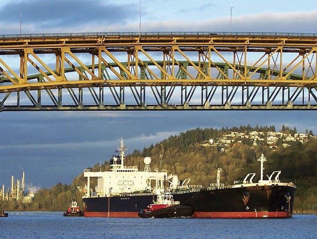 A partially loaded crude oil tanker is guided out of Burrard Inlet from Burnaby's Westridge Terminal next to the Chevron oil refinery