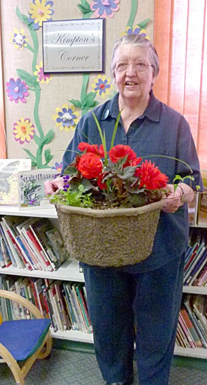 Frances Kimpton stands with her potted flowers and library plaque. Both were given by the Windermere Elementary staff to thank her for her continued hard work and dedicated volunteering at the school.