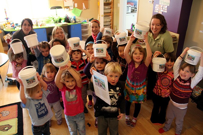 Kids and staff at the Sonshine Children's Centre excitedly show off their penny collection buckets for their new playground fundraiser.