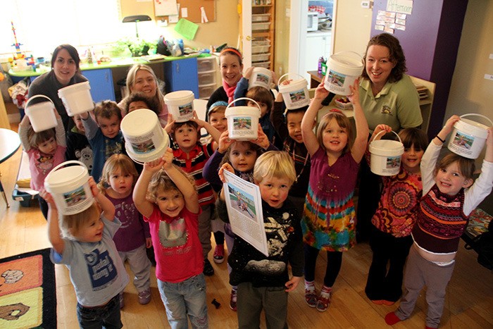 Kids and staff at the Sonshine Children's Centre excitedly show off their penny collection buckets for their new playground fundraiser.
