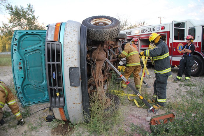 Volunteer firefighters with the Invermere fire department stabilize a rolled car during a simulated accident.