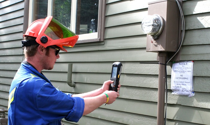 Smart meter installer photographs a sign posted to refuse replacement of mechanical power meter