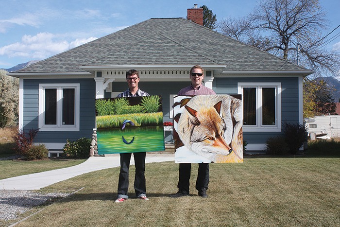 Jon Howlett (left) and Geoff Hill hold up Howlett's original works of art in front of the house that realtor Hill is wanting to showcase