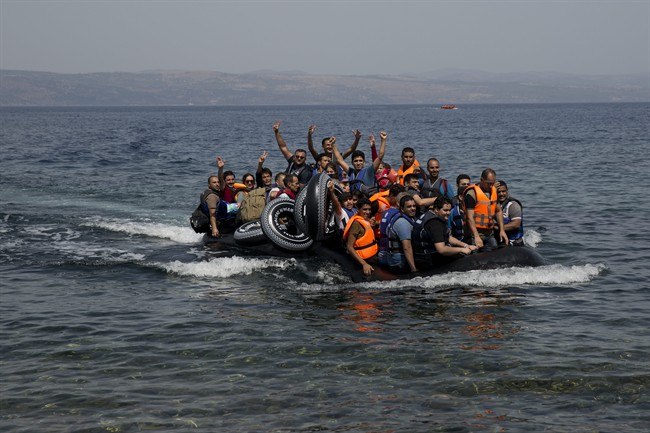 Syrian refugees arrive aboard a dinghy after crossing from Turkey