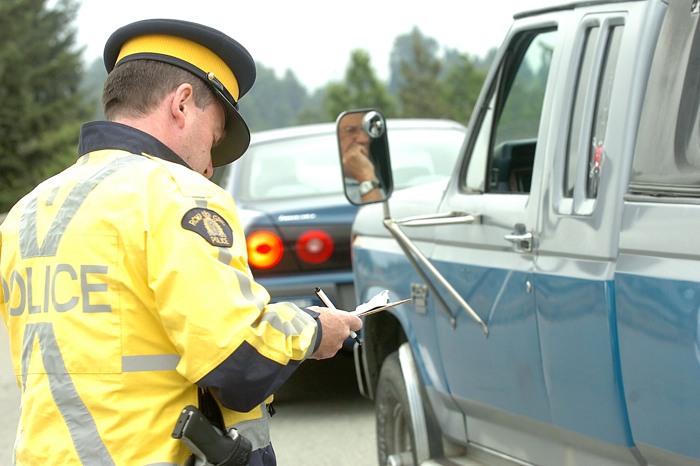 An RCMP officer writes a traffic ticket in Surrey.