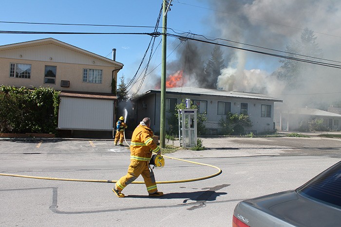 A firefighter douses the flames of a fire that destroyed an abandoned motel in Radium on Sunday