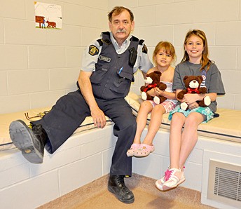 Staff Sgt. Marko Shehovac sits with two visiting girls during the Columbia Valley RCMP detachment open house May 11.