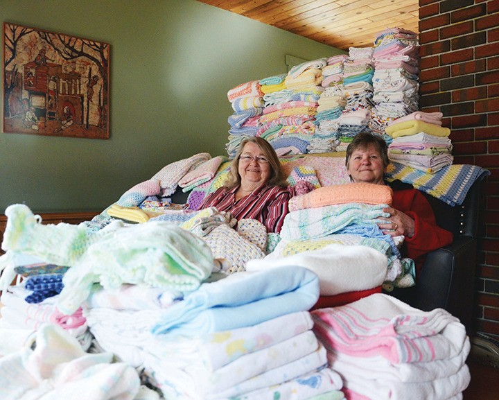 Go-Go Sisters Shirley Dahl (left) and Florence Raven sit amongst the mass of baby blankets they are sending to a hospital in Uganda