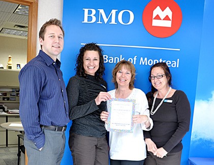 BMO staff hold up their advertisement for their Relay for Life barbecue.