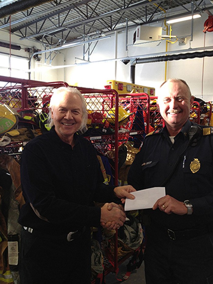 Danny Osborne presents fire chief Jim Miller with a cheque for $5
