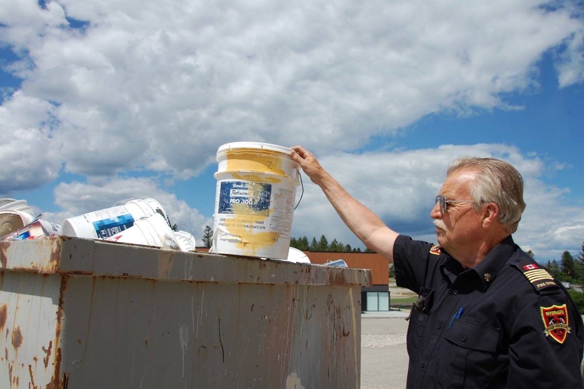Invermere Fire Chief Roger Ekman inspects paint that does not belong at the paint drop-off spot outside the Invermere Fire Hall. The dumpster often gets filled with items that are not part of the paint recycle program.Photo by Lorene Keitch