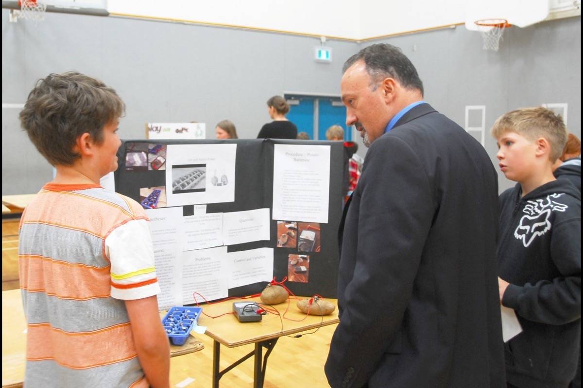 Rocky Mountain School District Superintendent Paul Carriere and student Karson Schick listen to Aidan Guest talk about his experiment. Photo by Lorene Keitch