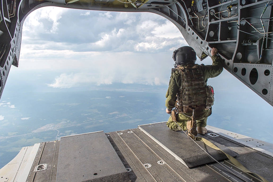 A Canadian Armed Forces Flight Engineer surveys the wildfires burning in British Columbia during a reconnaissance flight from a CH-147 Chinook during Operation LENTUS 17-04 in Kamloops British Columbia, on 12 July 2017. (Province of British Columbia)